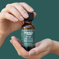 Hand holding a bottle of 'frankly real' all-purpose cleaner concentrate against a green background